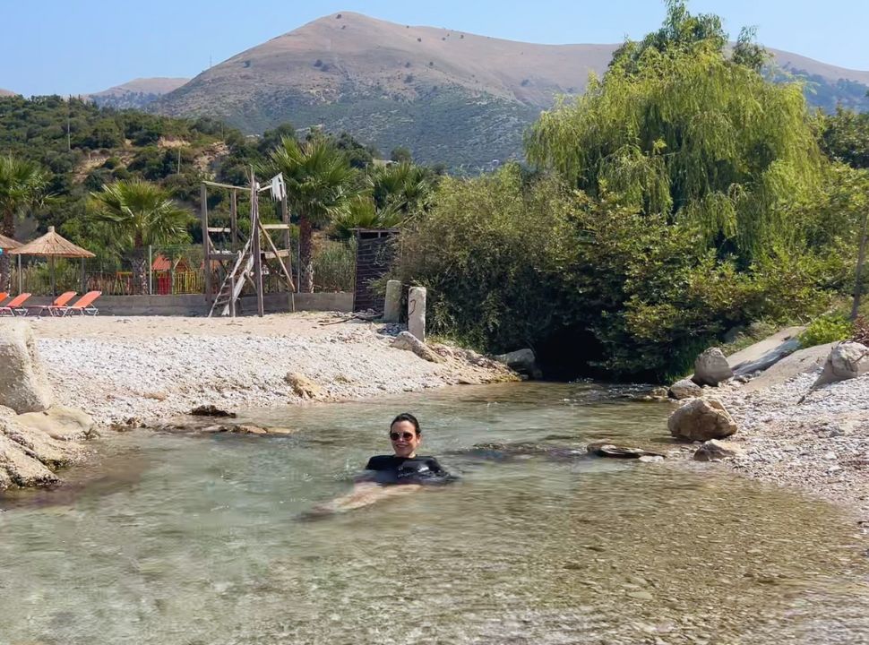 woman enjoying a little fresh water stream that flows straight into the ocean at Buneci Beach Albania