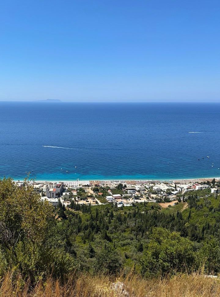 beach seen from the coastal road located in the mountains, beach is covered with sun beds and accommodation