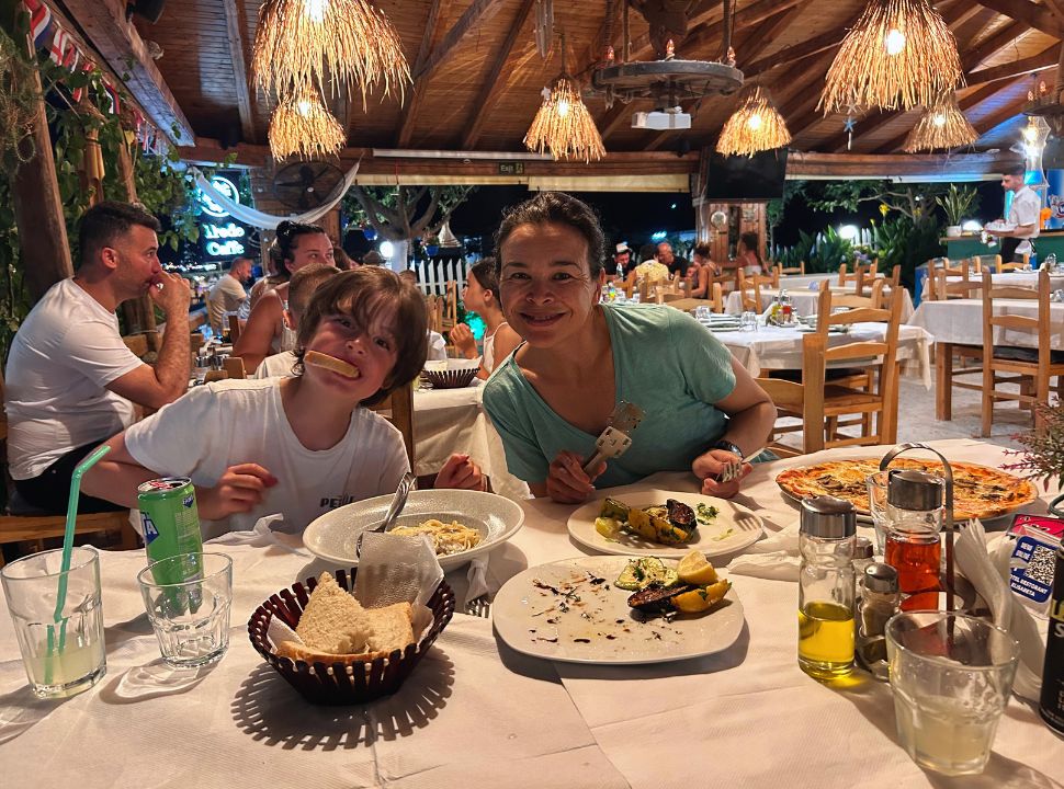 mother and son posing at dinner where they are enjoying pasta, pizza and grilled vegetables along the Albanian Riviera