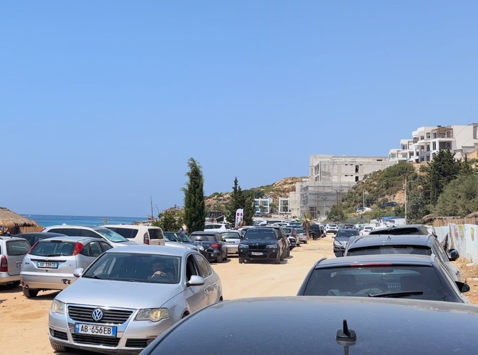 road full with parked cars, beach is on the left and right are newly constructed accommodation at Drymades Beach Albania