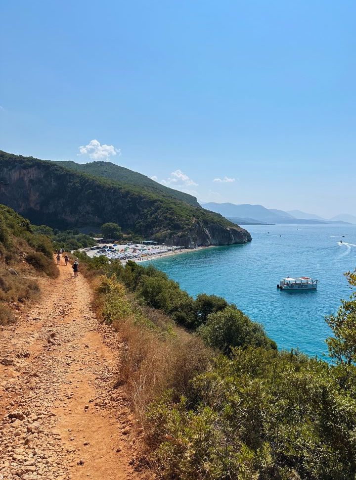 dirt road with rocks leading to Gjipe beach, which is visible in the far distance set within the canyon in Albania