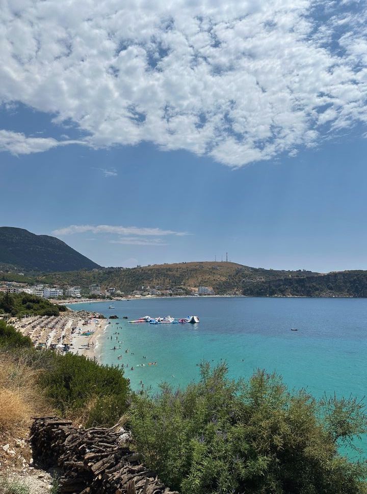 small beach with lots of sun loungers, inflatable water park in the turquoise blue water in Himare Albania