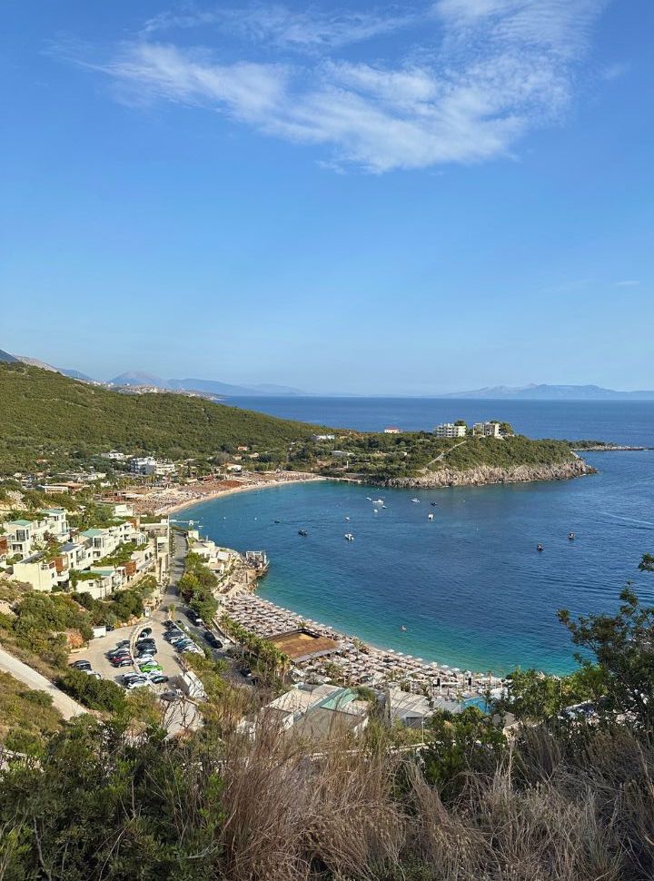 bay with a beach covered with sun loungers, hotels along the beach at Jala Albania