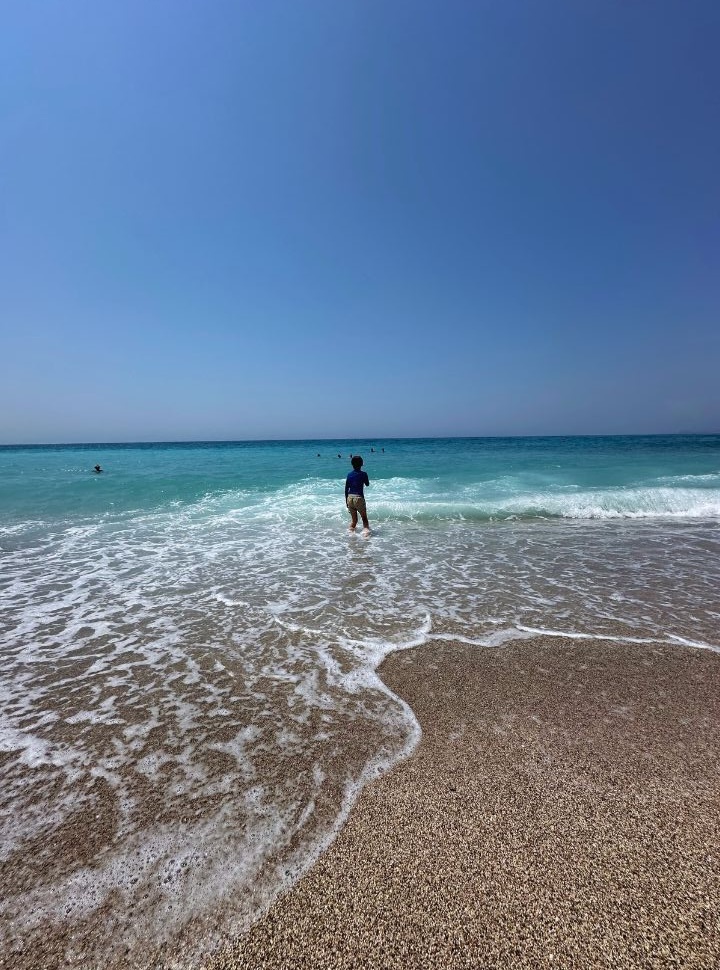 boy standing in the shallow water of the blue ocean at Lukove beach