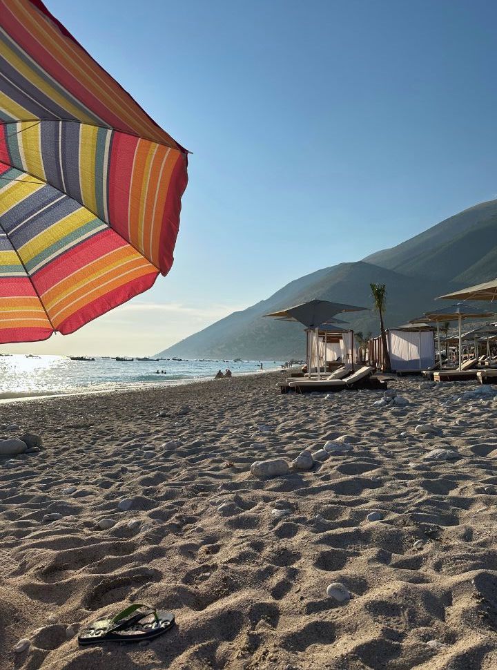 colorful umbrellas with in the back row of sun loungers at Green Coast beach Albanian Riviera