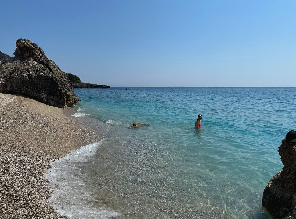 woman swimming in a quiet part of the Dhermi beach, rocks are found along the waterfront