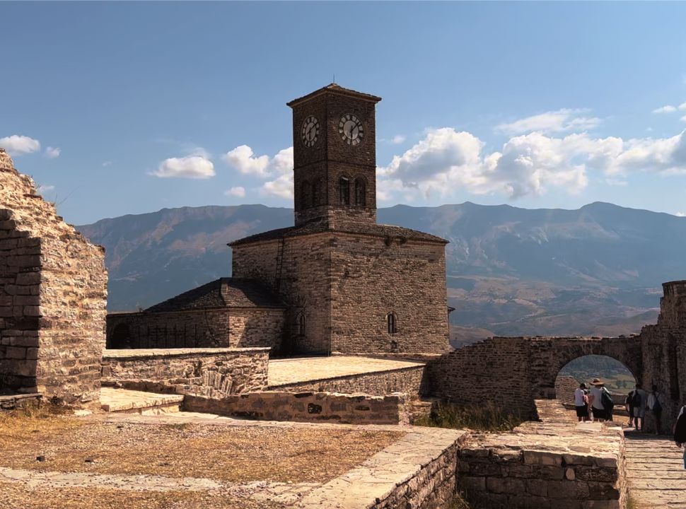 the clock tower of Gjirokastër castle with the mountain range in the back