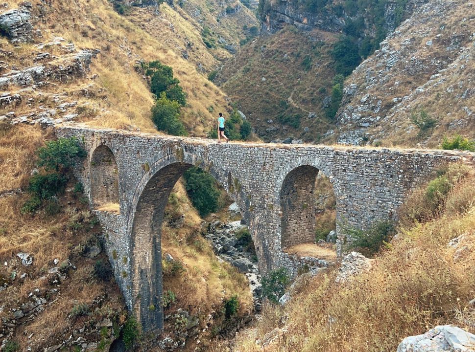 woman crossing an ancient aqueduct set in a beautiful valley in Gjirokaster Albania