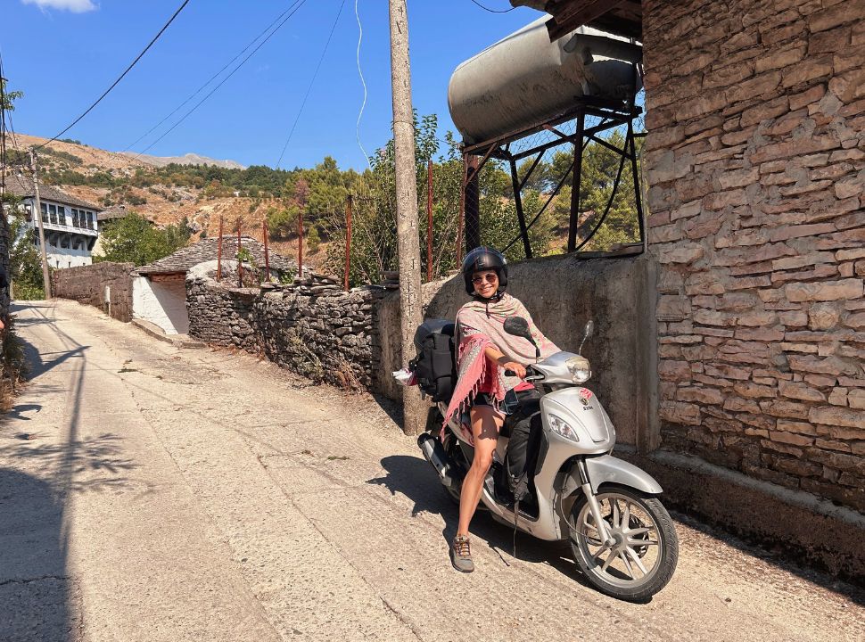 woman keeping her motorscooter steady on a steep down hill street in Gjirokaster Albania