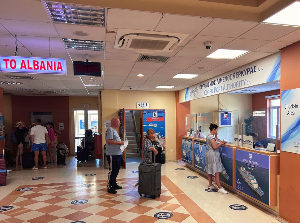 man and woman standing in line for a information desk at the ferry terminal in Corfu Greece