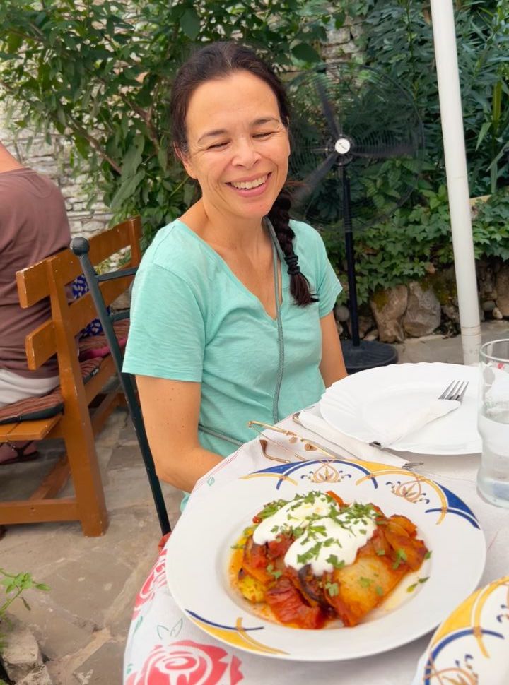 woman at a table with a delicious Albanian dish, ready to have lunch