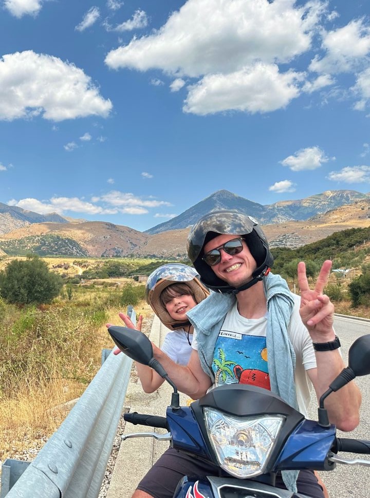 father and son posing for picture with stunning mountain range in the back