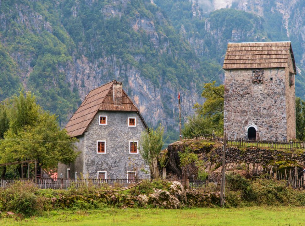 farm house at Theth village with a tall mountain wall in the back in Albania