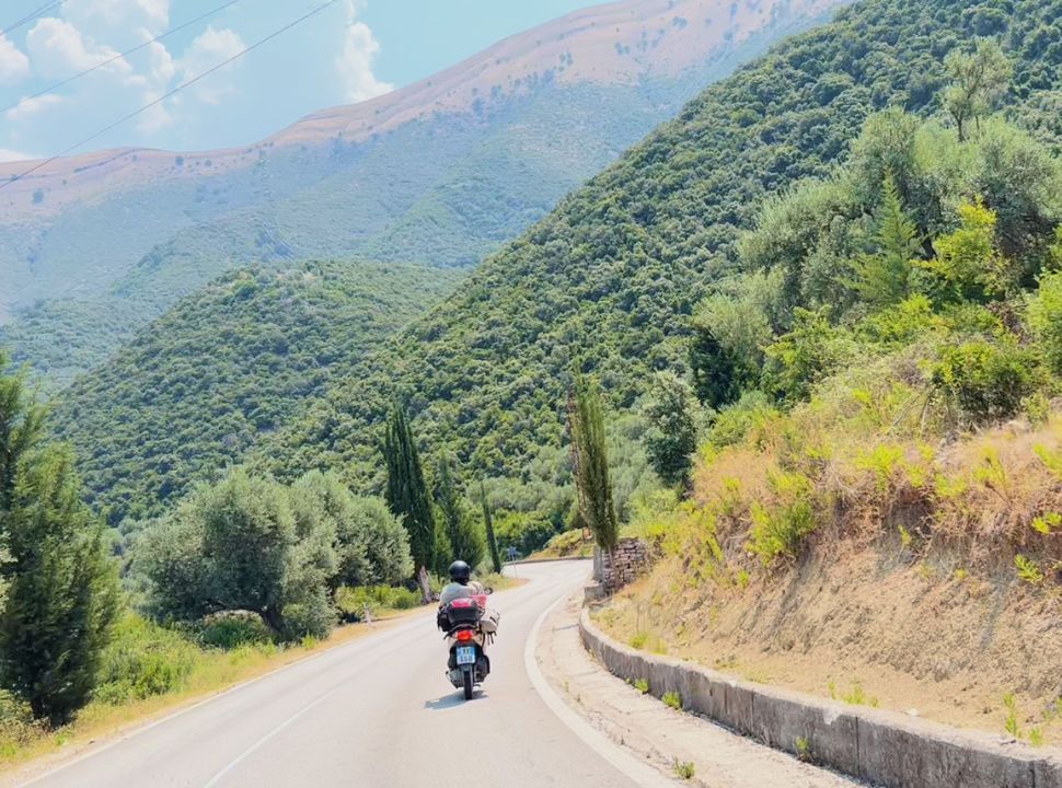 woman driving on a motor scooter through the mountain landscape 