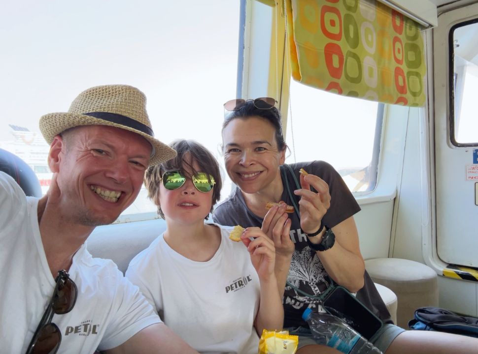 family posing for a picture with snacks in their hands on the ferry from Corfu to Albania