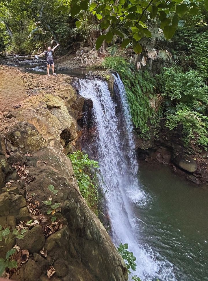 woman standing on top of the waterfall surrounded by lush vegitation in Mauritius