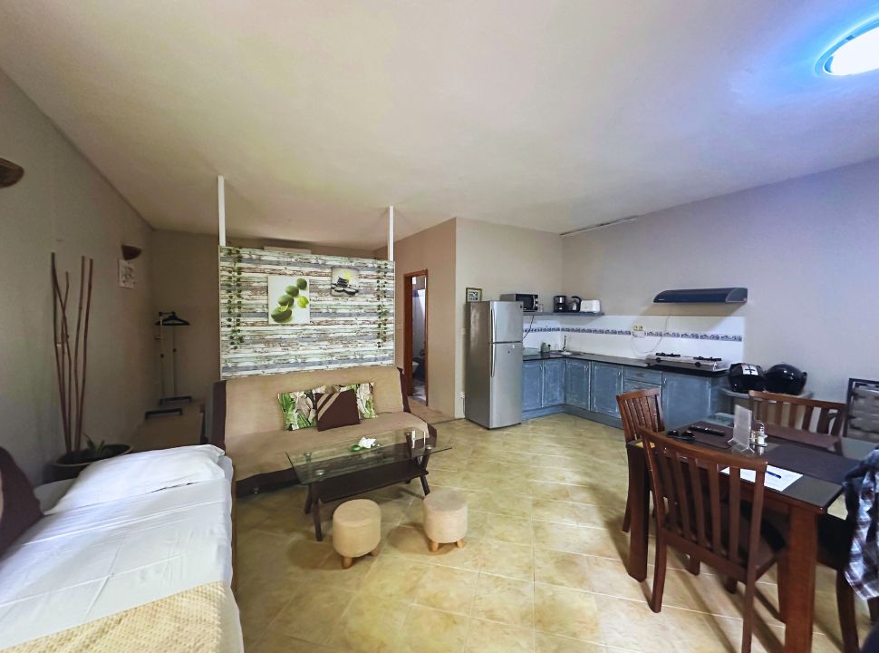 an accommodation in Mauritius with a kitchen, eating table, seating area, an extra bed and in the back a door to the bathroom. The double bed is located behind the screen.
