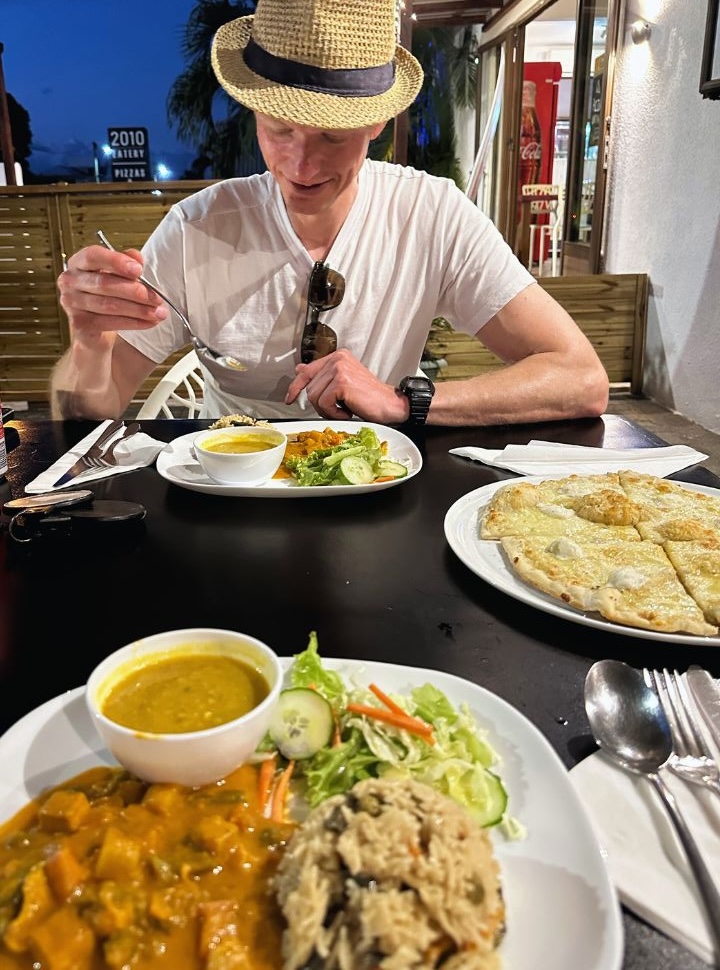 man eating biriyani, curry and dahl on the outdoor terrace of a restaurant in Mauritius