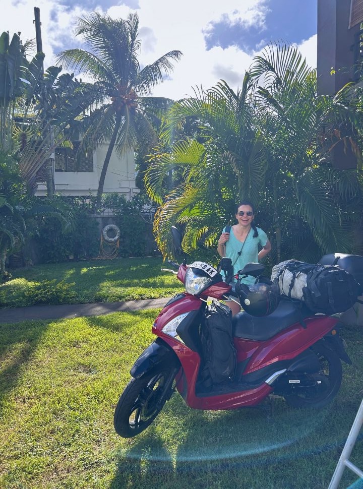 woman preparing her motorbike and bags in a tropical garden in Mauritius