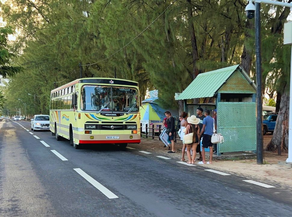 local bus stopping at a bus stop where people are waiting to board at Flic en Flac beach Mauritius