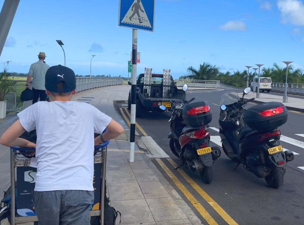 two motor scooters parked at the departure terminal which are dropped off by a pick-up owned by the rental company in Mauritius