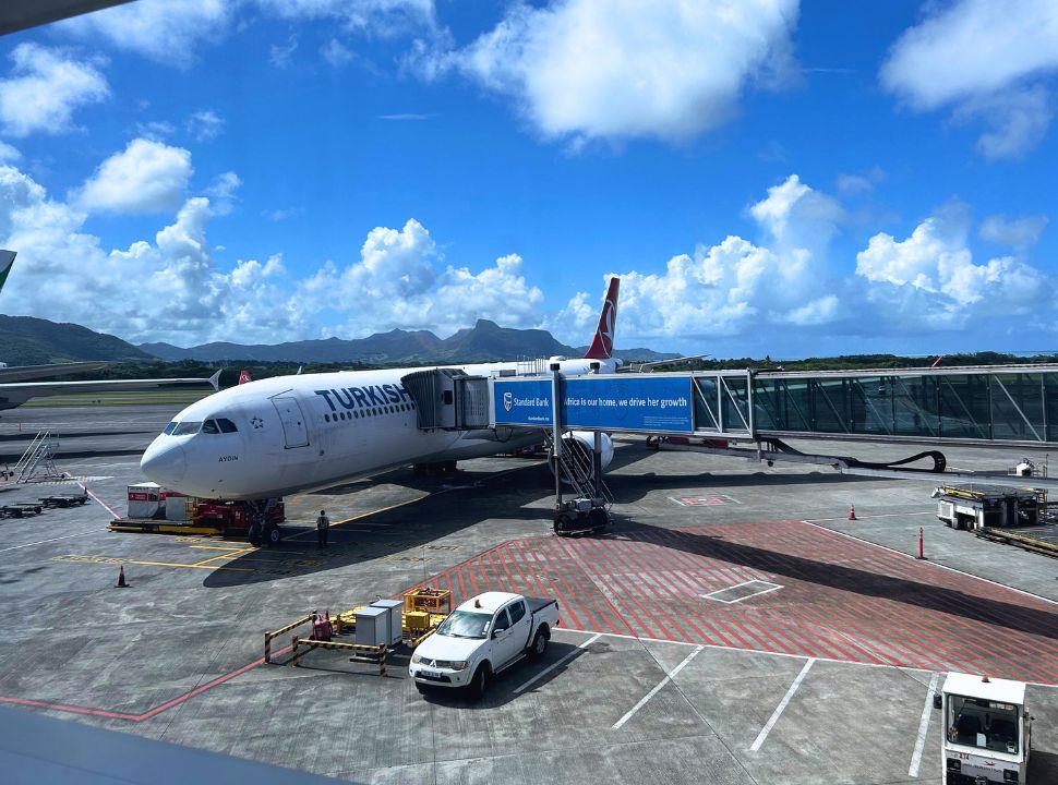 Turkish Airline plane parked at Mauritius airport, mountains are dominating at the back.