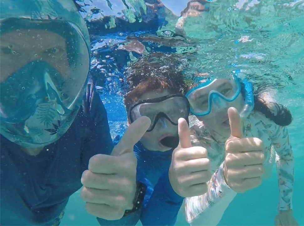 family of three posing for a picture under water while snorkeling in Mauritius