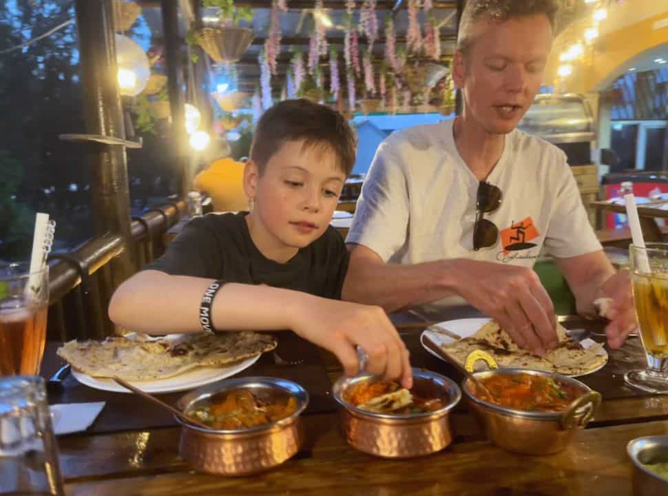 father and son eating naan and curry at a restaurant in Mauritius