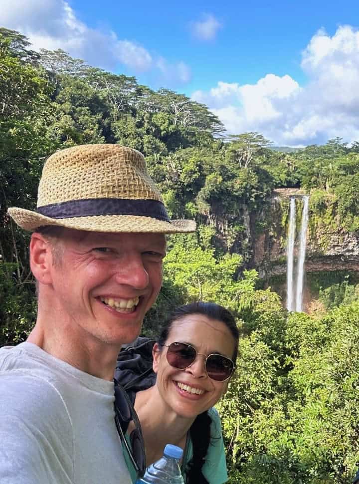 couple posing a chamarel waterfall, Mauritius travel tips bring mosquito repellent when heading to green lush areas. 
