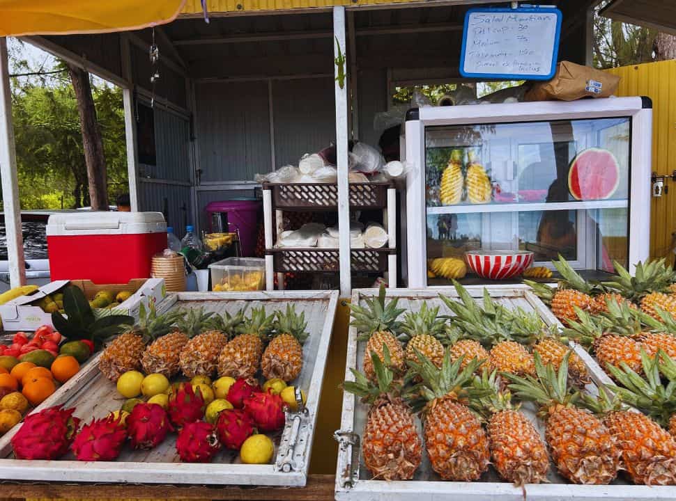 food stall selling fruit salads at a beach in Mauritius, there is a selection of pineapples, dragon fruit, lemon, watermelon, and orange