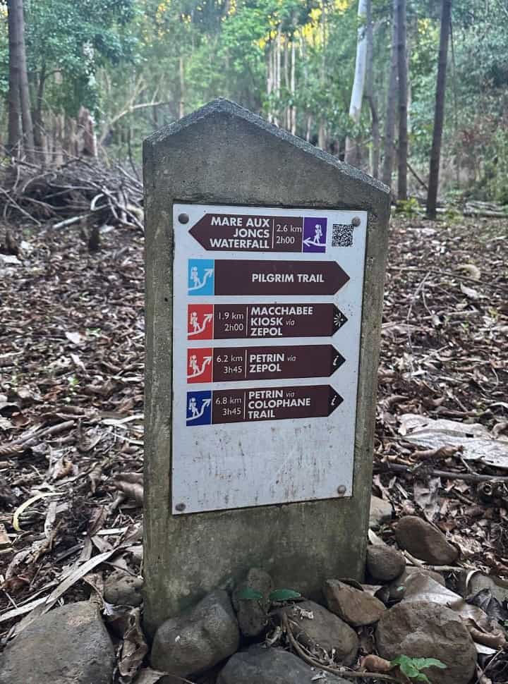 a pole with 5 signs indication the various trails, distance and how long it would take is mentioned