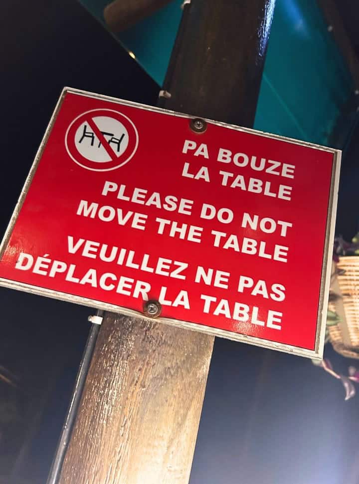 a red sign with three languages with the request: please do not move the table