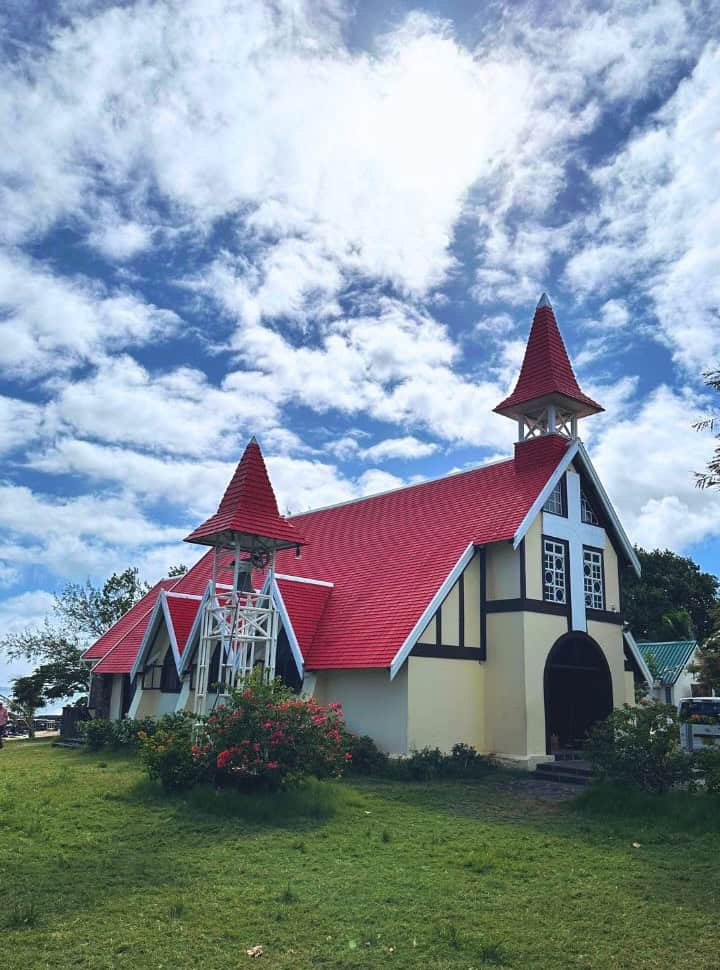white church with a red roof surrounded by green grass in Mauritius