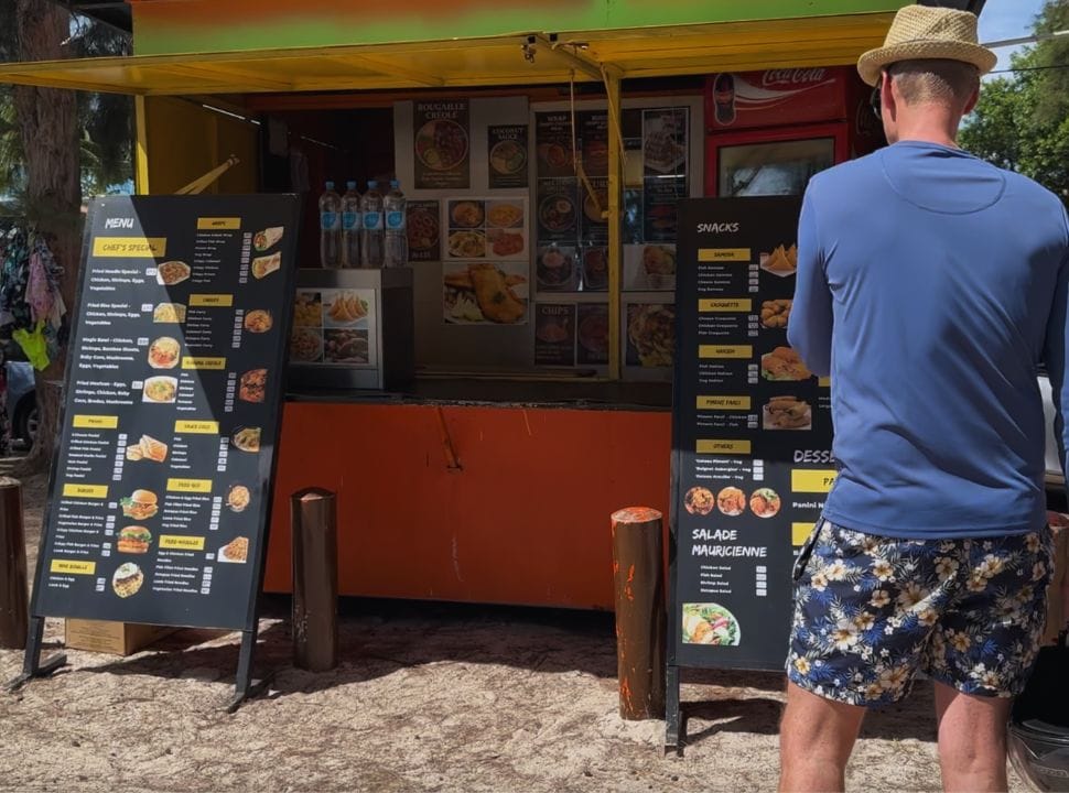 man checking out the menu at a food stall at the beach in Mauritius