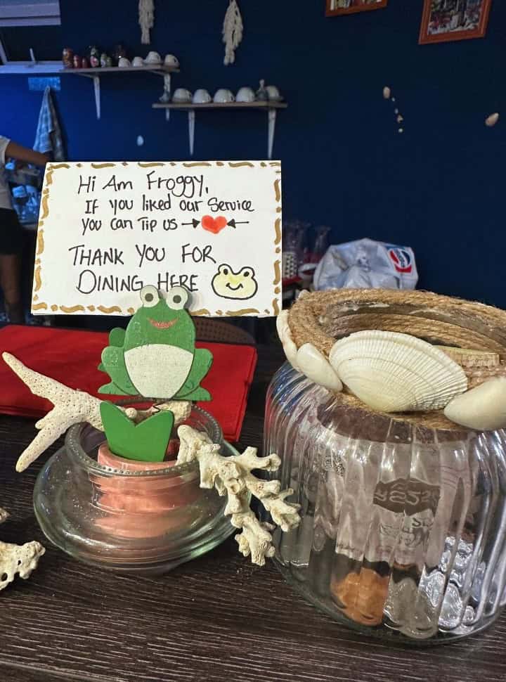 tipping jar with a frog that holds up a sign stating: hi am froggy, If you like our service you can tip us, thank you for dining here
