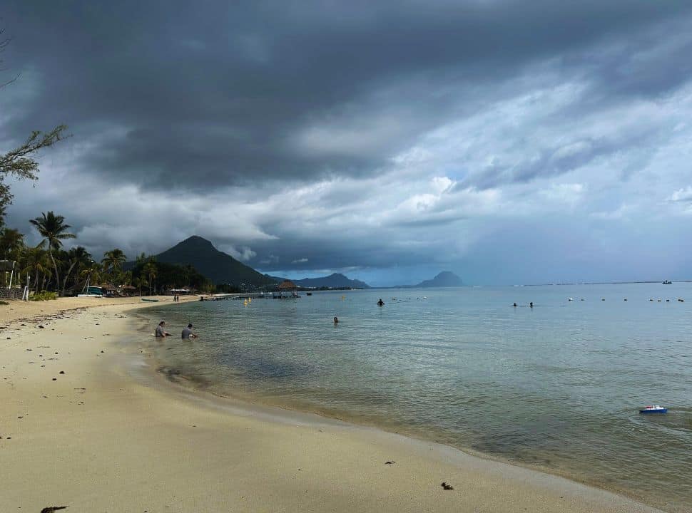 a tropical beach with heavy dark cloud looming above in Flic en Flac. Mauritius travel tips avoid the cyclone season. 