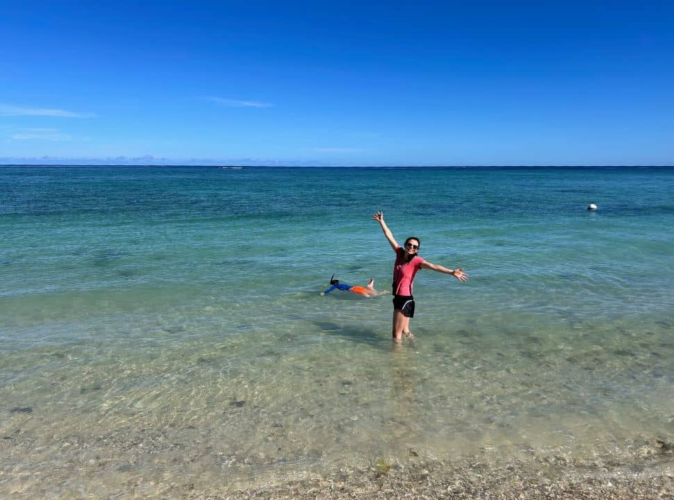 mother and son in the tropical clear water in Mauritius, the son is snorkeling while the mother is posing happily for the picture