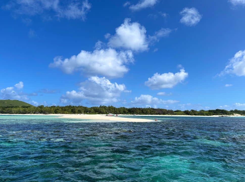 white sand bank surrounded by stunning blue water, the island has green vegetation and more white beaches set in Mauritius