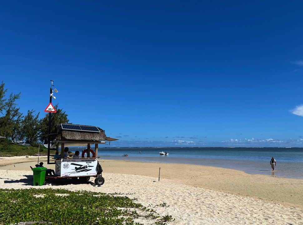 small cart with solar panels and people selling or providing info for the Mauritius Underwater Waterfall, leaving from La Prairie beach, it is low tide