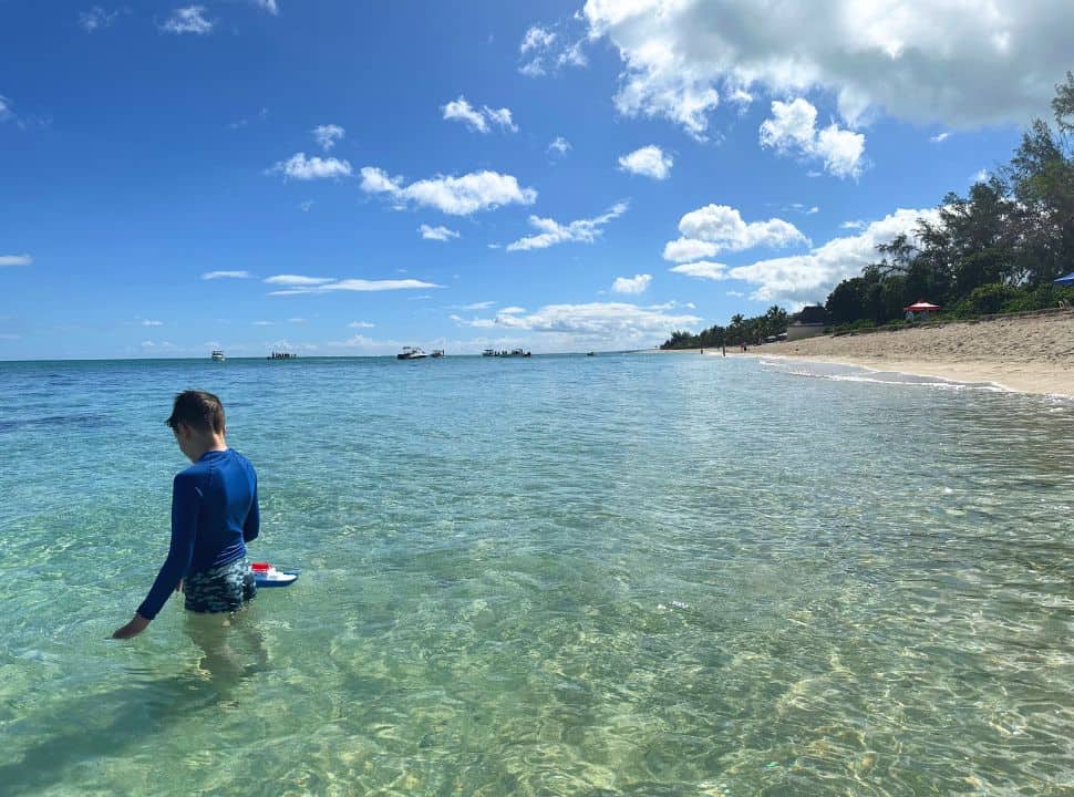 boy playing with his boat in the clear ocean water in Mauritius
