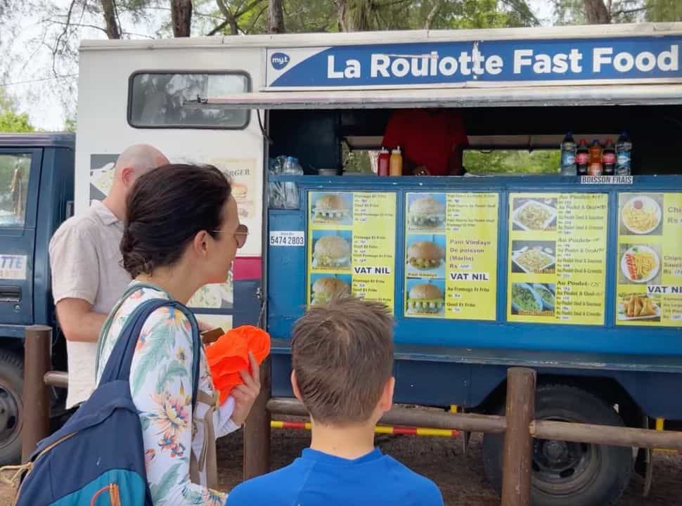 mother and son looking at the menu of the food truck at the beach offering local Mauritian food 