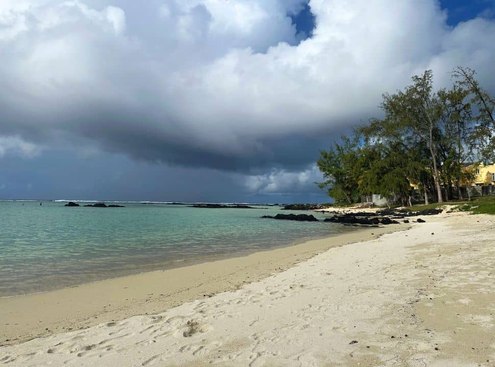 dark heavy clouds approaching the soft sanded beach with turquoise water in Mauritius