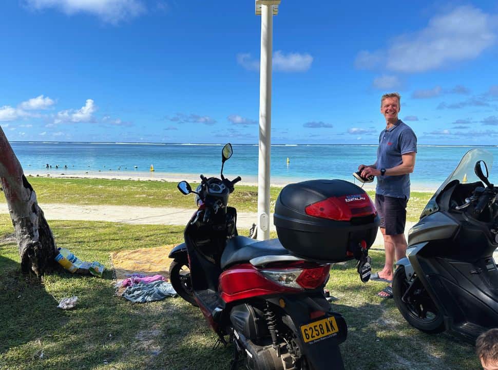 man standing between two parked motorscooters, right at the beach in Mauritius