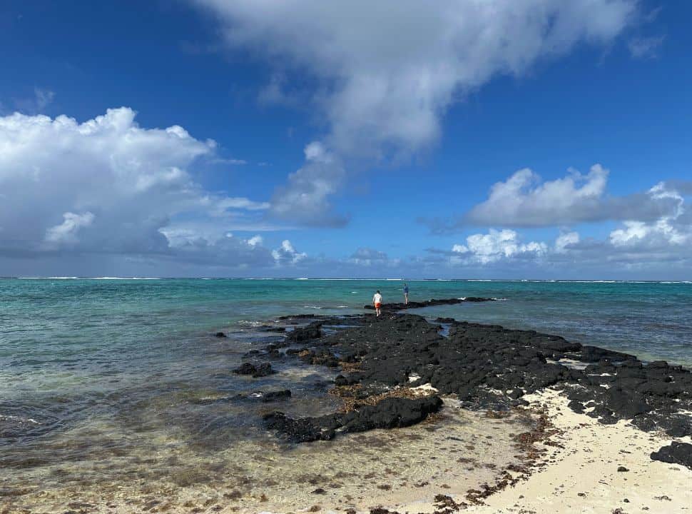 father and son walking along the black rocks that lead into the ocean at low tide at Palmar beach