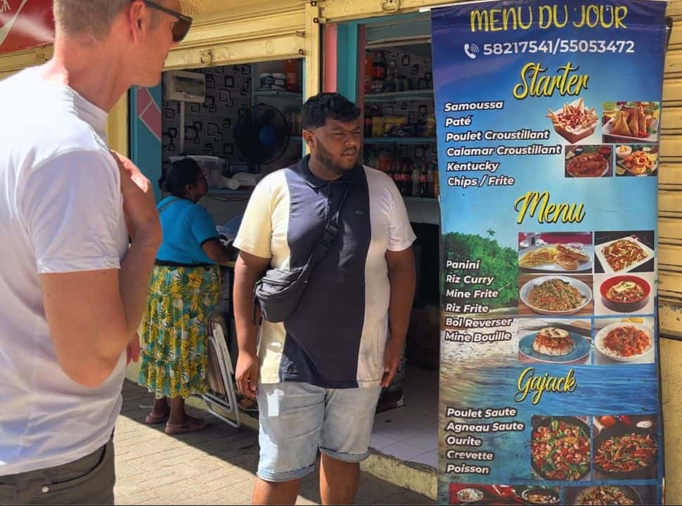 restaurant owner giving information on their menu to a man looking for some lunch at st felix beach. 