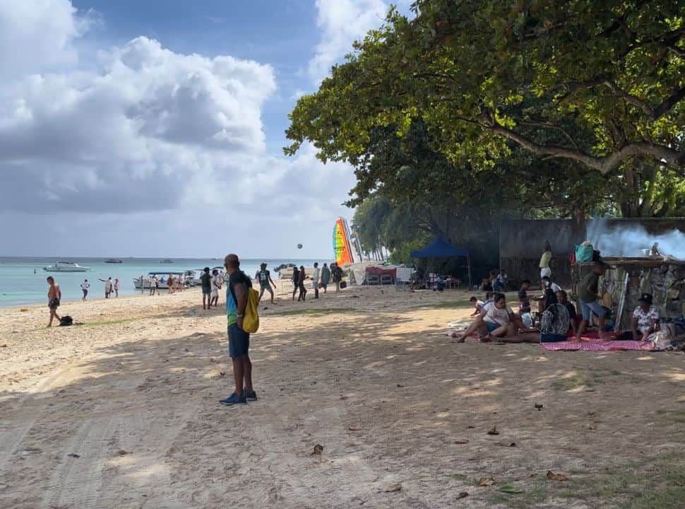 a busy beach, with people gathered together playing with a ball, having a barbeque at trou aux biches Mauritius