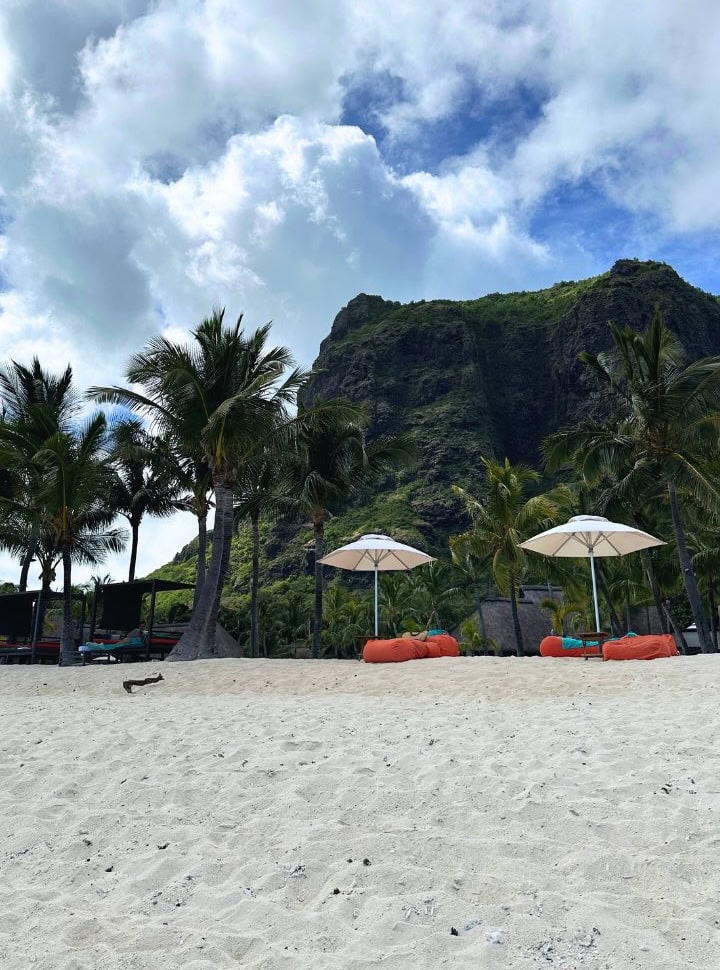 sun umbrellas with beach bags set on the tropical beach with the Le Monte Brabant Mountain in the Back, a beautiful setting for couples to stay in Mauritius