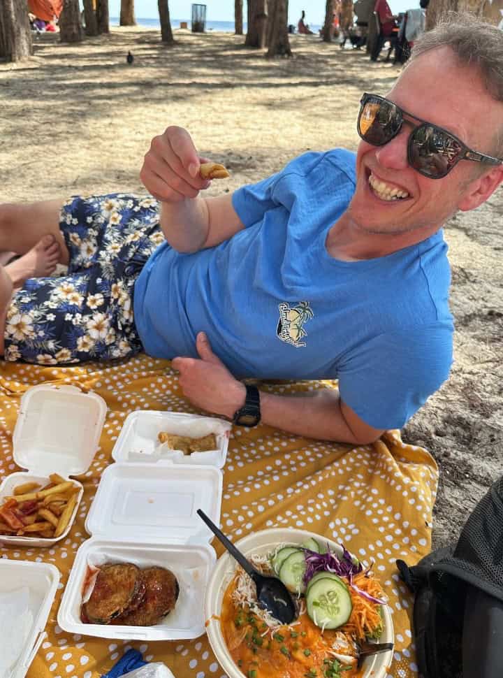 man eating local Mauritian food at the beach, there are four types of dishes he can choose from