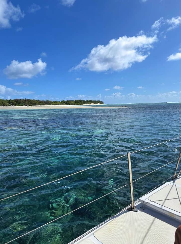 view of a tropical island with white sand and green vegetation, picture is taken from a boat 