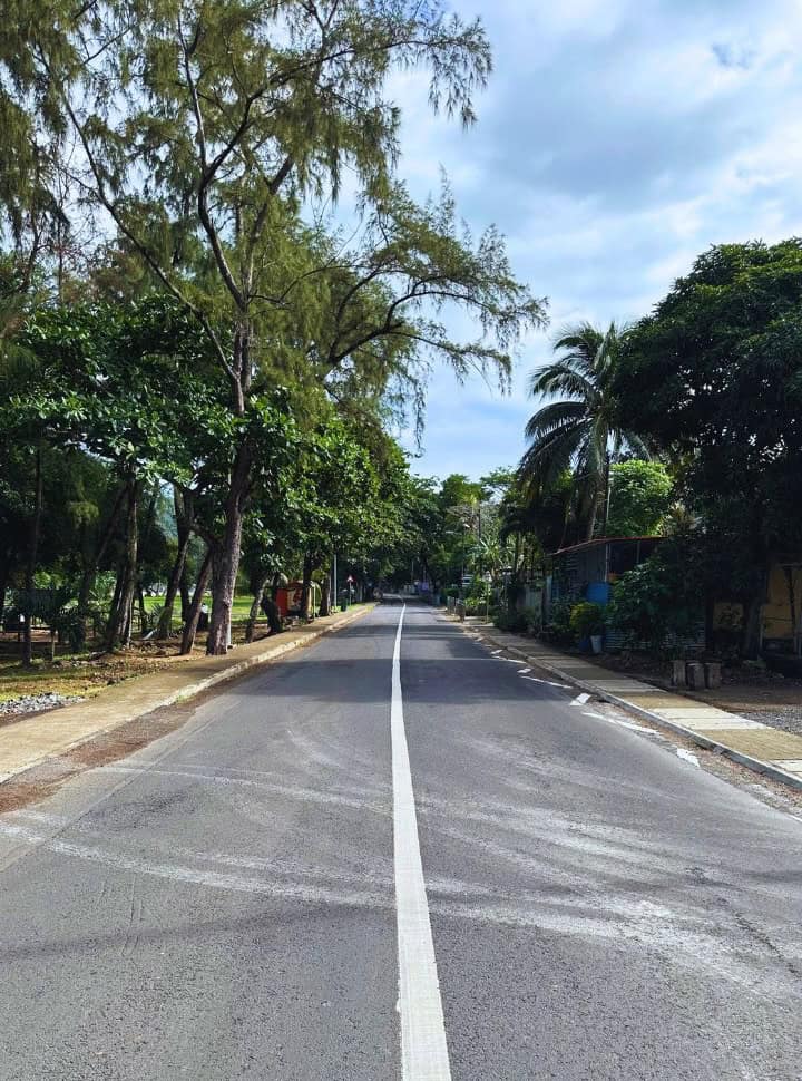 a quiet main road with a park on one side and houses on the right at Le Morne Brabant Mauritius
